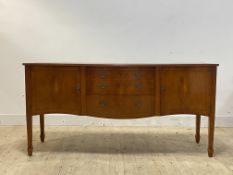 A Regency style yew sideboard of serpentine outline, three drawers flanked by cupboards, raised on