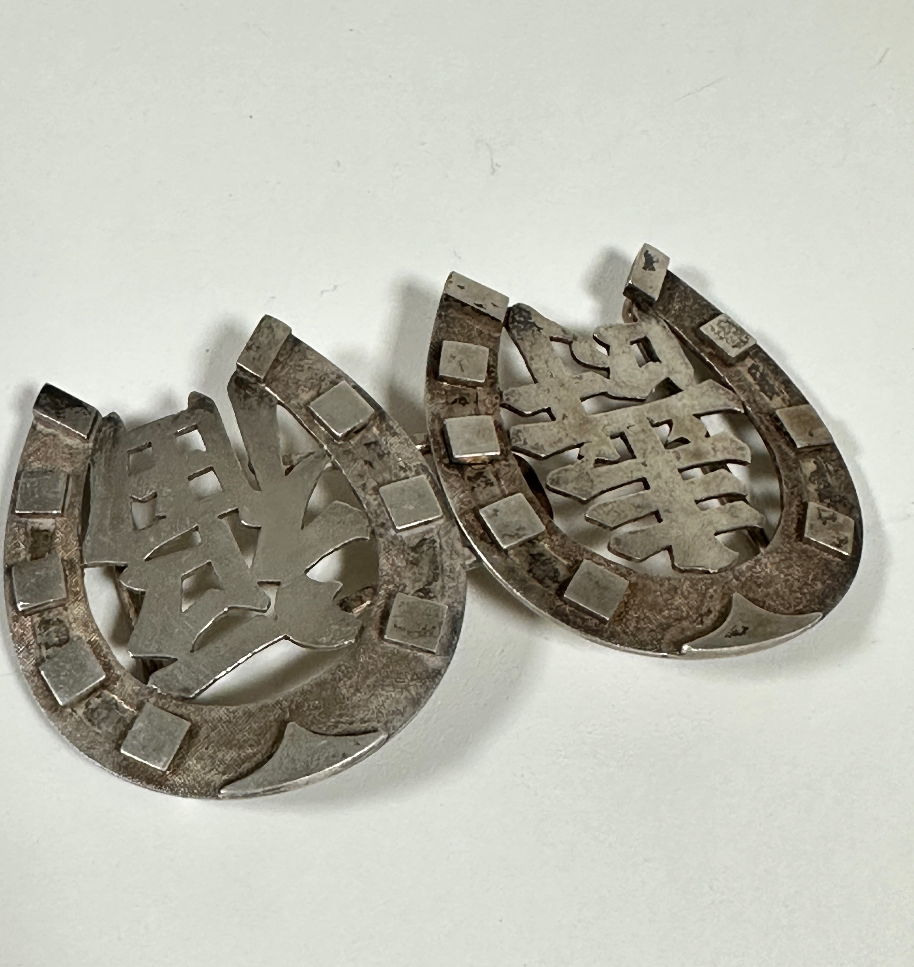 A pair of Chinese horseshoe shaped white metal belt buckles, stamped verso HC, with Chinese