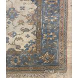 A large Indian wool pile carpet, the ivory field of floral design, within a blue border 360cm x