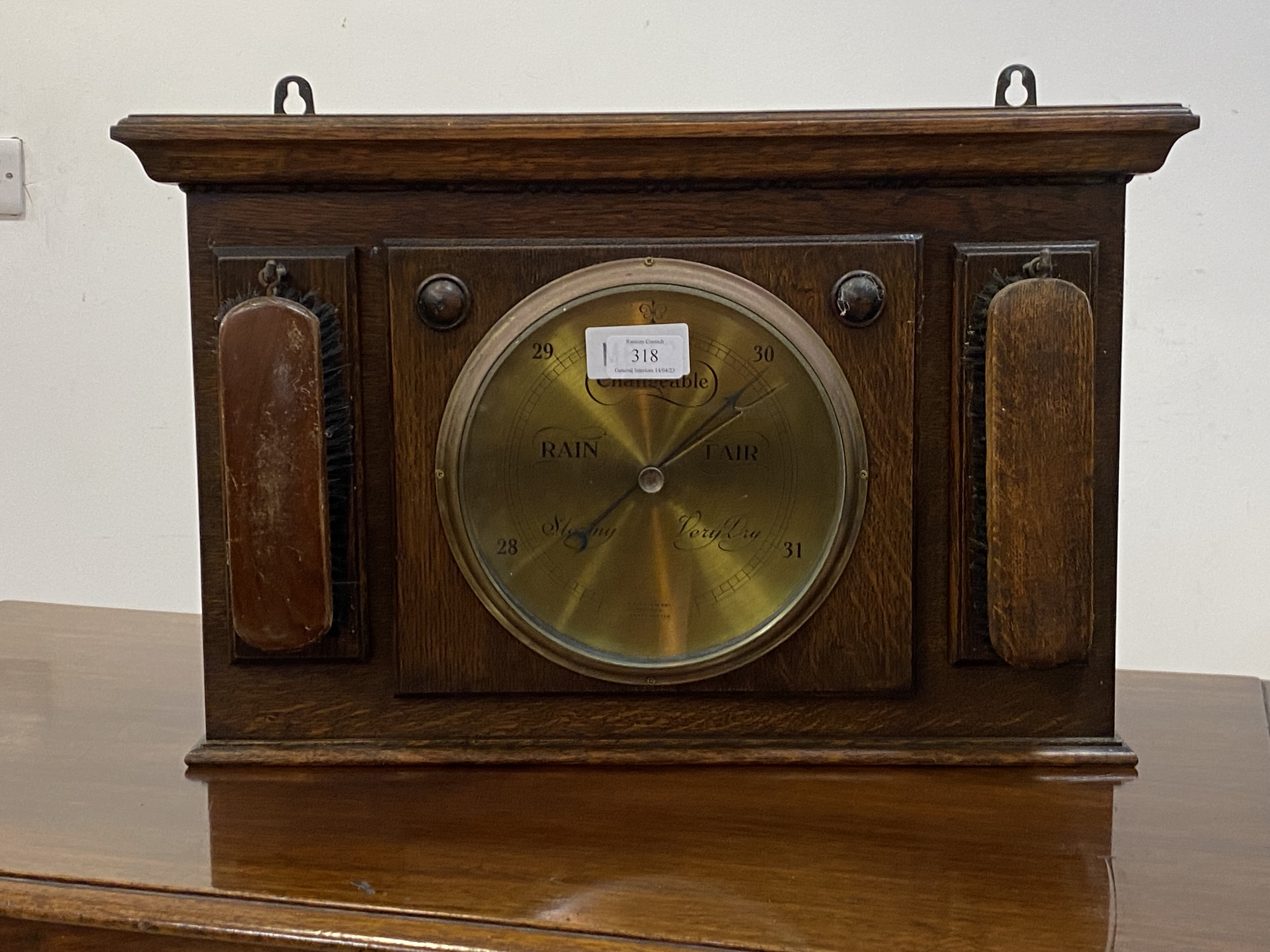 An oak cased aneroid barometer, the frame with two clothes brushes W54cm