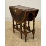 An early 20th century oak gate leg drop leaf table, the carved circular top over bobbin turned