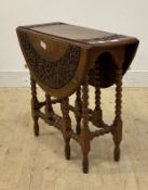 An early 20th century oak gate leg drop leaf table, the carved circular top over bobbin turned