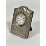 A modern R Carr quartz movement bedside clock with modern silver mounted chased frame, with plush