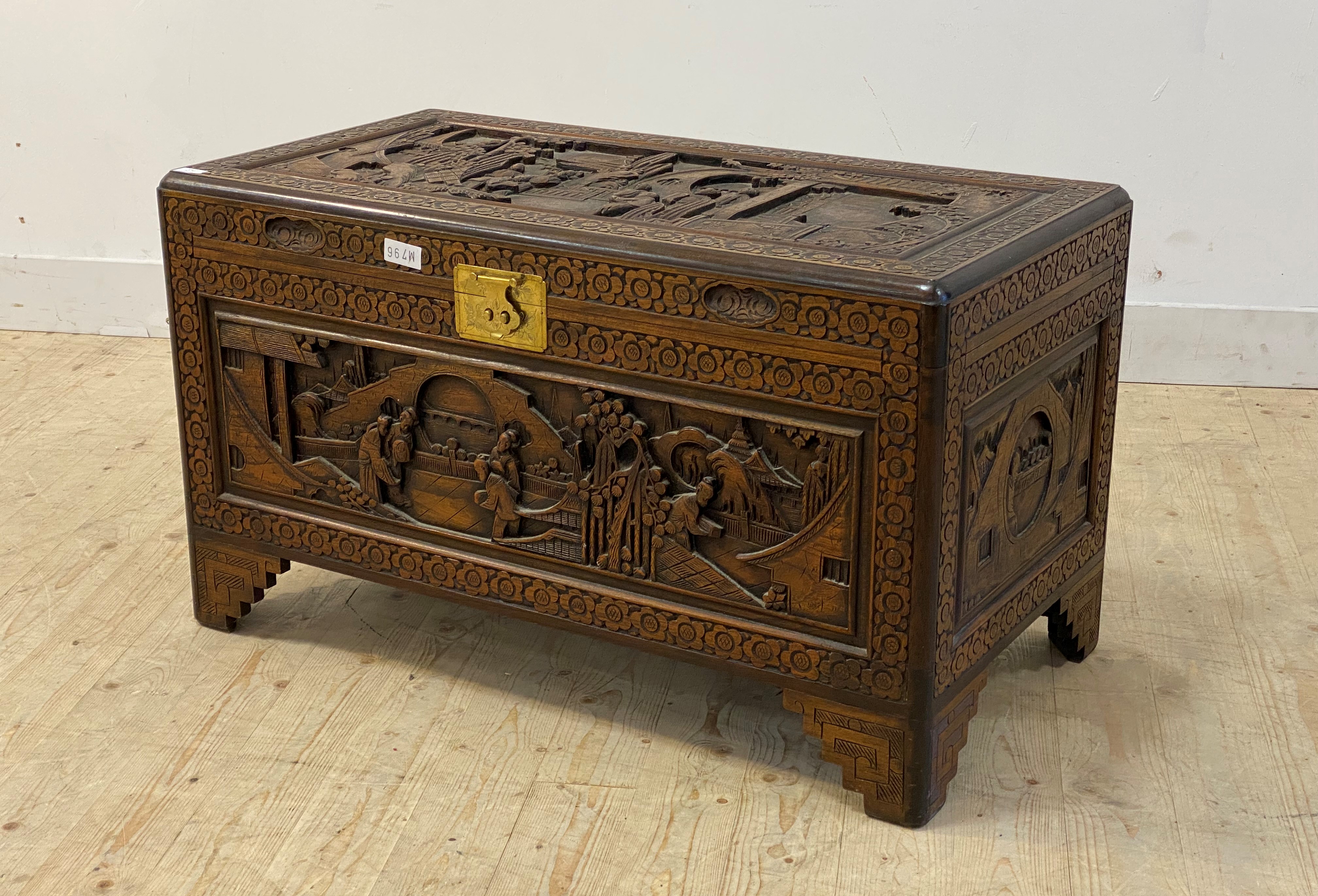 A Chinese camphor wood blanket box, each side with typical relief carvings, the hinged lid lifting