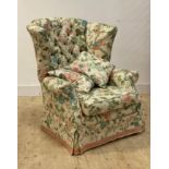 An early 20th century button back upholstered wingback armchair, raised on ebonised and moulded