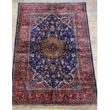 A Persian style silk pile rug, the blue field with arabesques within a deep red guarded border 297cm