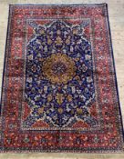 A Persian style silk pile rug, the blue field with arabesques within a deep red guarded border 297cm