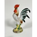 A pottery cockerel decorated with polychrome enamels, raised on shaped moulded base, (h 33cm x