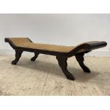 A carved hardwood scroll end window bench of Regency design wiyth overstuffed split cane covered