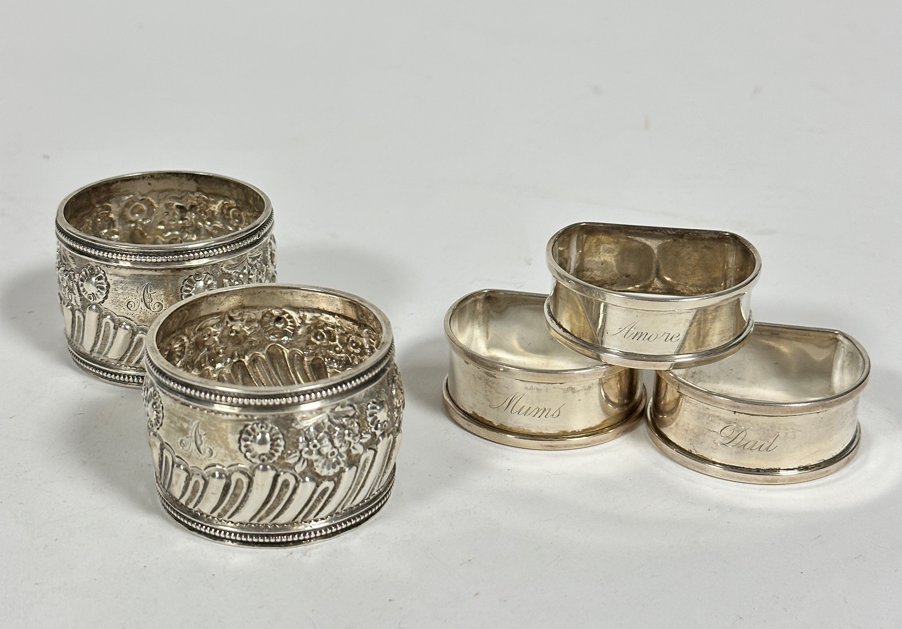 A pair of London silver chased circular napkin rings with beaded borders and stylised floral