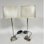 A pair of modern chrome finish column table lamps raised on stepped bases with pleated silk oval