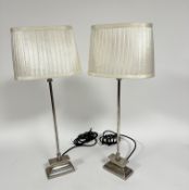 A pair of modern chrome finish column table lamps raised on stepped bases with pleated silk oval