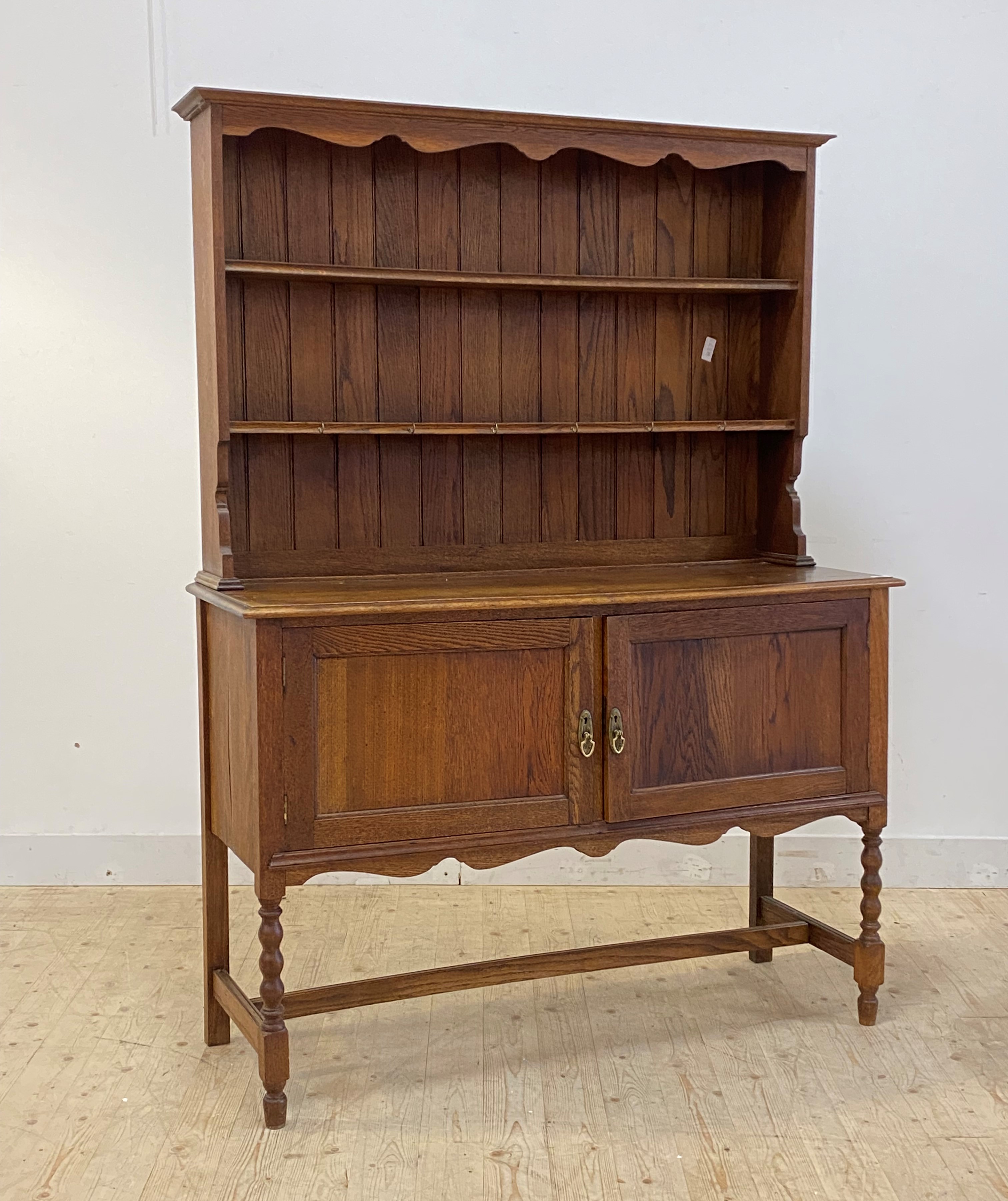 An early 20th century oak dresser, with two height plate rack over twin panelled cupboard doors to