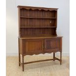 An early 20th century oak dresser, with two height plate rack over twin panelled cupboard doors to