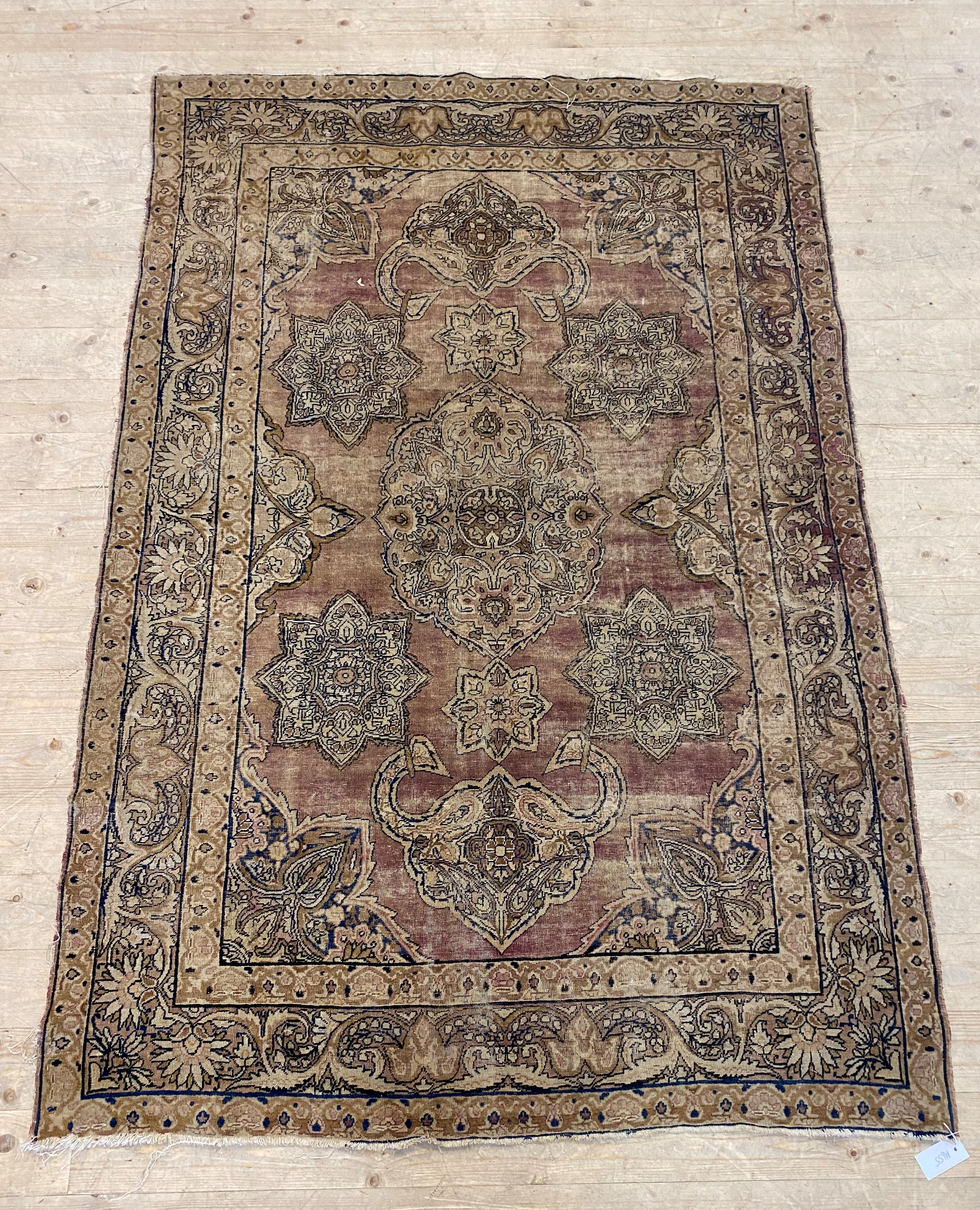 A Persian style rug, the faded red field decorated with lotus heads and bordered 200cm x 134cm