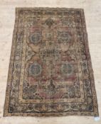 A Persian style rug, the faded red field decorated with lotus heads and bordered 200cm x 134cm