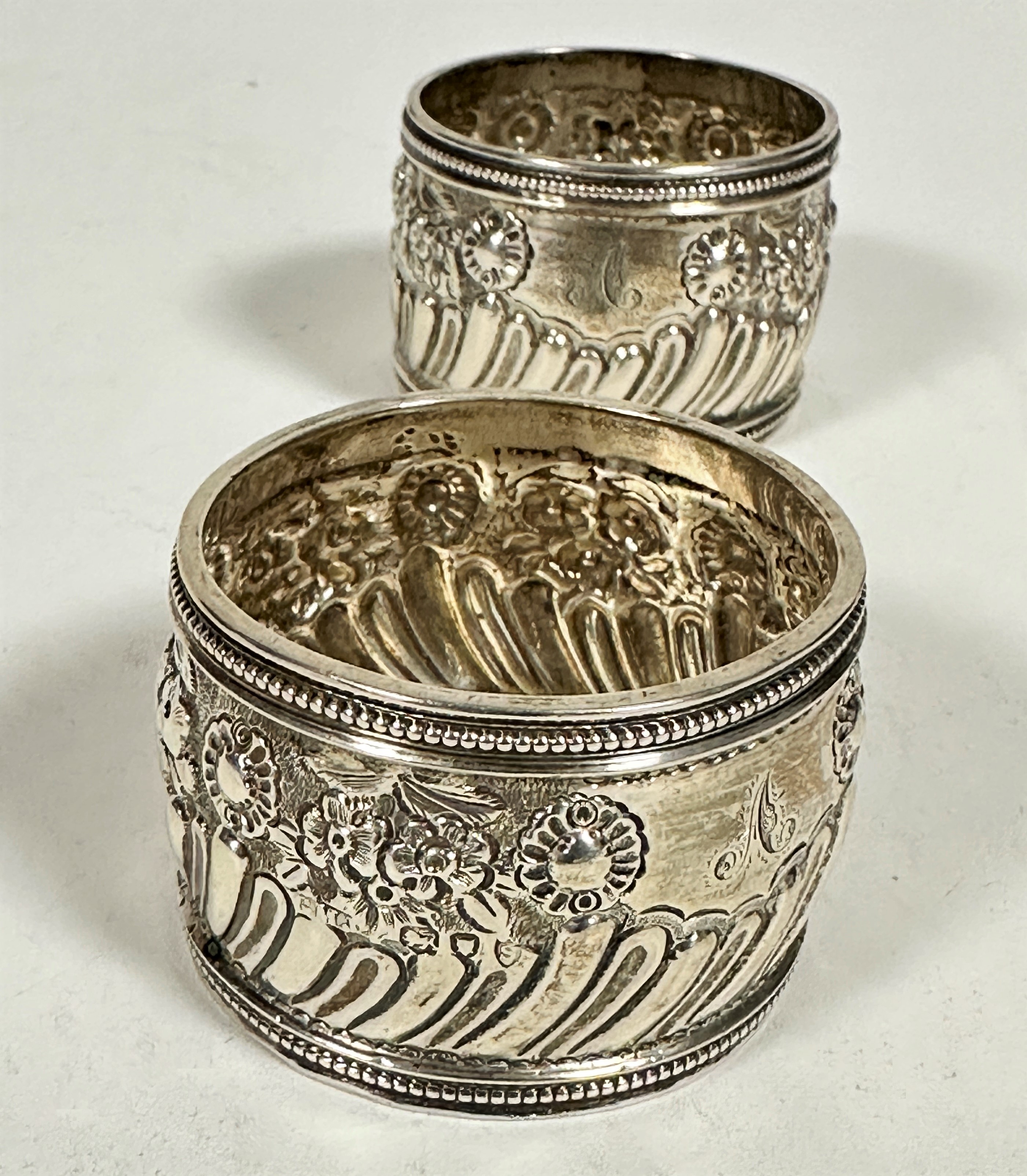 A pair of London silver chased circular napkin rings with beaded borders and stylised floral - Image 2 of 2