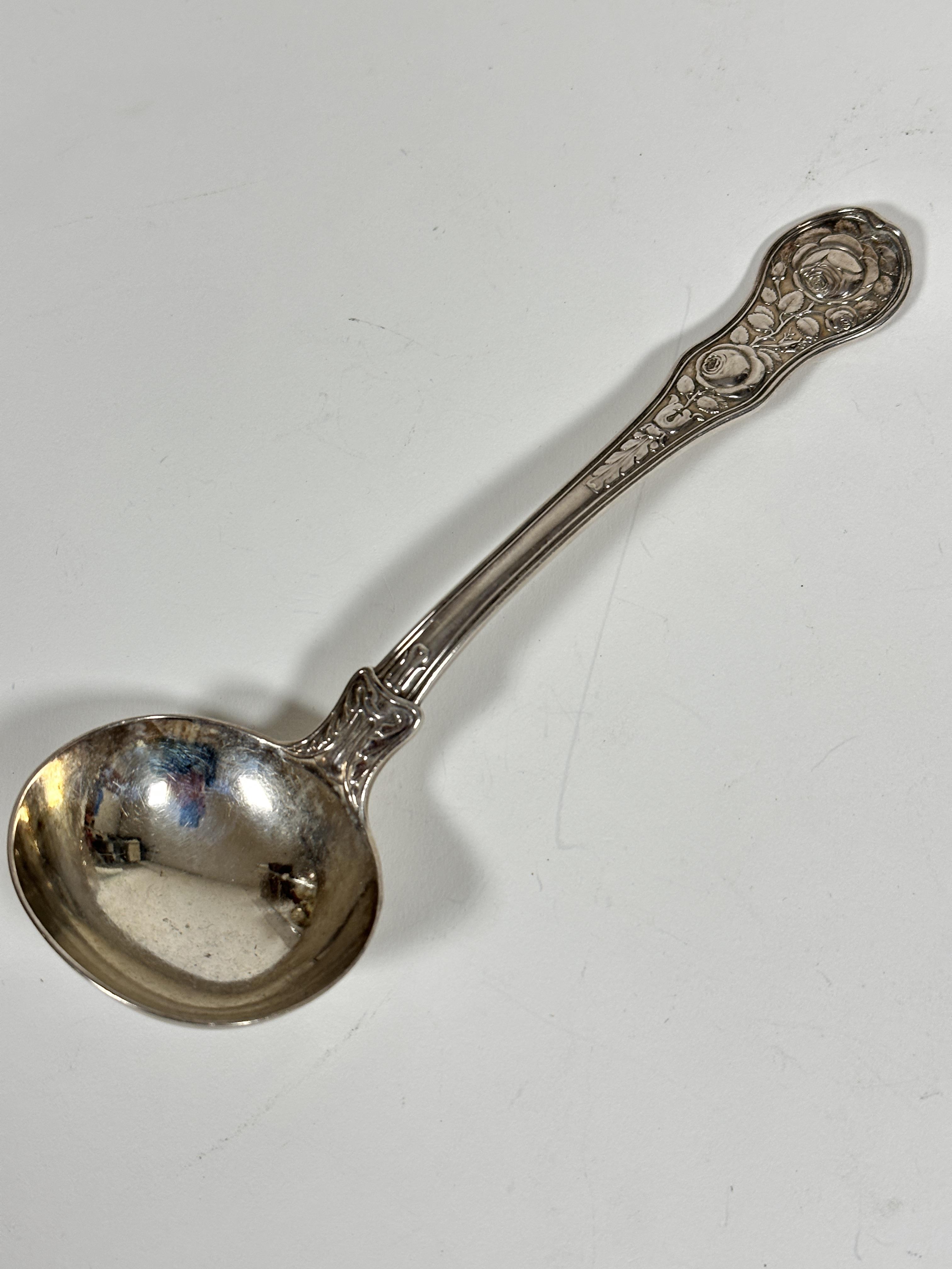 A Georgian silver shaped sauce ladle with chased rose and leaf design with fan shell chased rear