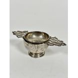 A London 1953 silver tea strainer with pierced C scroll design, complete with circular stand, on