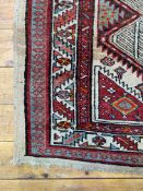 A hand knotted Caucasian rug, the ivory field with geometric pole medallion within a guarded border.