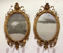 A pair of 19th century gilt-composition girandole mirrors, each oval plate within a leaf-moulded