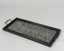 A pair of Chinese silk needlework sleeve panels mounted as a tray, c. 1920, the panels worked in