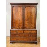 A George III mahogany linen press, the dentil cornice over two panelled doors with applied roundels,