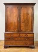 A George III mahogany linen press, the dentil cornice over two panelled doors with applied roundels,