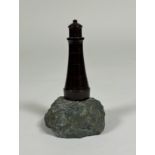 A Cornish red serpentine model of a lighthouse, mounted on a rock. 15.5cm