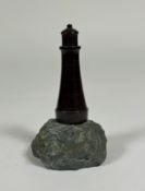 A Cornish red serpentine model of a lighthouse, mounted on a rock. 15.5cm