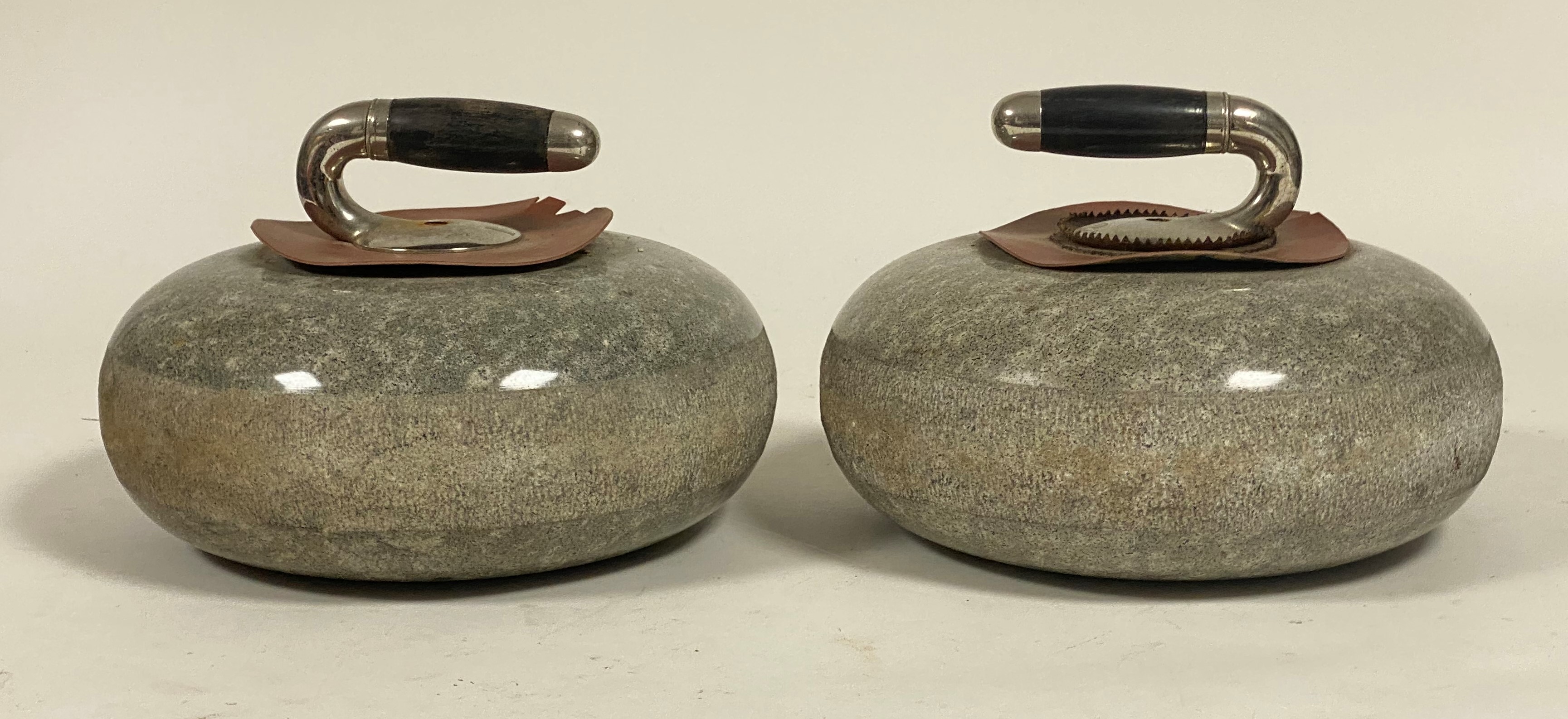 A pair of granite curling stones, with white metal collars and ebonised handles. Diameter c. 27cm