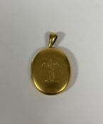 A late 19th century gold (unmarked) locket, oval, opening to twin glazed compartments, engraved to