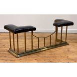 A leather-upholstered brass club fender, the corner seats in black leather supported on a frame of