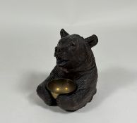 A 19th century Black Forest tobacco jar, carved as a seated bear, the hinged head with inset glass