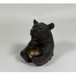 A 19th century Black Forest tobacco jar, carved as a seated bear, the hinged head with inset glass