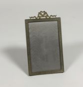 An Edwardian gilt-metal photograph frame, the rectangular aperture within a ribbon-bound reeded