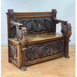 A profusely carved German oak hall settle, late 19th century, the back carved with a frieze