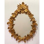 A carved giltwood oval wall mirror, the frame formed as repeating flower heads and trailing oak