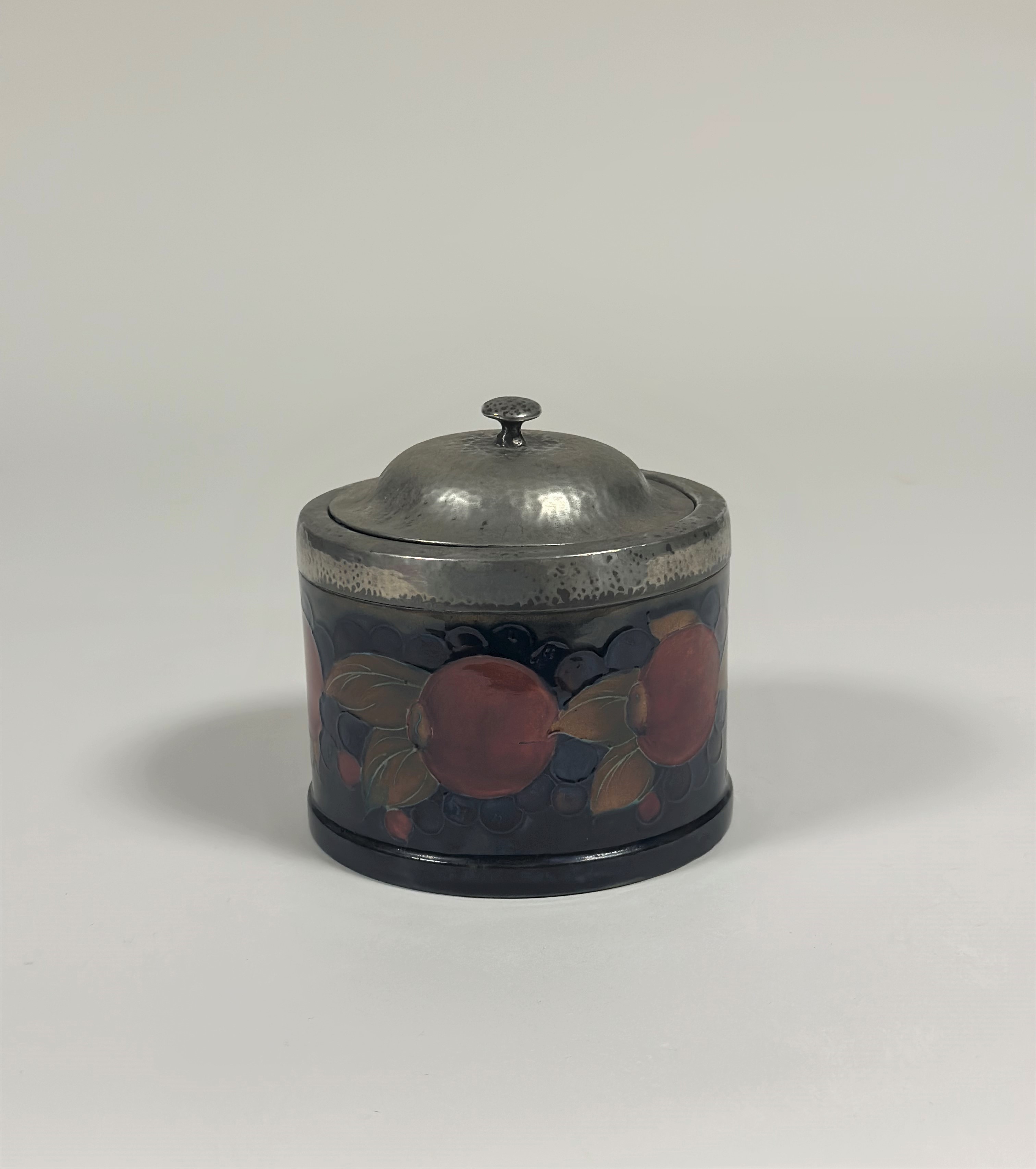 A William Moorcroft Pomegranate pattern pewter-mounted biscuit barrel, the planished domed cover