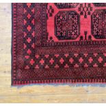 A hand knotted Afghan Bokhara type rug, in a traditional palette, decorated with two rows of guls