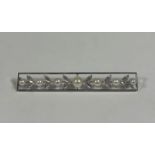 A large 9ct white gold and cultured pearl bar brooch, c. 1920, set with seven graduated pearls