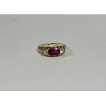 An Edwardian three stone ruby and diamond ring, the cushion-cut ruby between a pair of brilliant-cut
