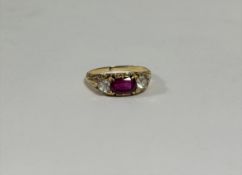 An Edwardian three stone ruby and diamond ring, the cushion-cut ruby between a pair of brilliant-cut