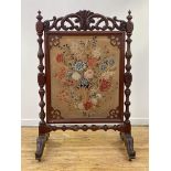 A large mid-Victorian mahogany needlework fire screen, the rectangular panel worked in polychrome