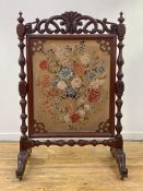 A large mid-Victorian mahogany needlework fire screen, the rectangular panel worked in polychrome