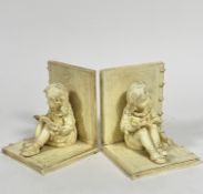 A pair of composition bookends with seated girl figures reading, (16cm x 13cm x 12.5cm)