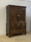 An 18th century oak linen press, the dentil cornice over twin arched panelled doors enclosing a void