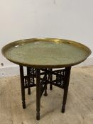 An Eastern brass tray top table raised on a folding base, H57cm, D69cm