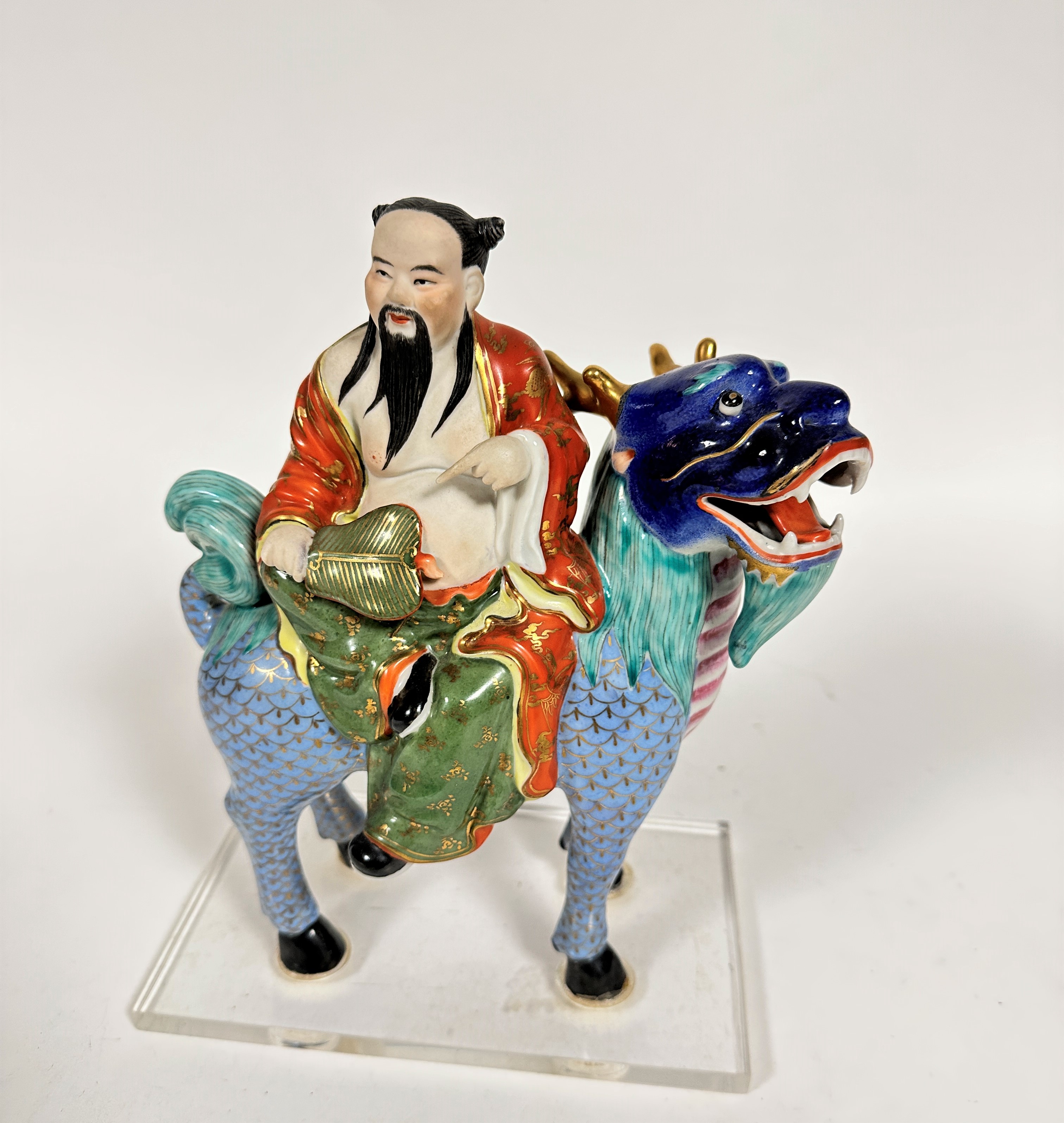 A Japanese porcelain Buddhist figure riding on a mythical stag, decorated with polychrome enamels,