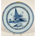 An 18thc Dutch Delft plate, the centre circular panel with stylised pine trees and building enclosed